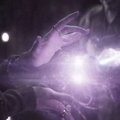 a person holding a cell phone in their hand with purple light coming from it's fingers