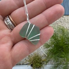 a hand holding a green sea glass necklace