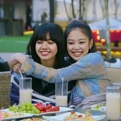 two women sitting at a table with plates of food and drinks in front of them