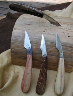 three knives are lined up next to each other on a piece of wood with a knife sharpener in the middle