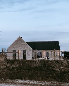 an old brick house sitting on top of a grass covered field next to a tree