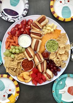 a plate full of food with chips, fruit, and dips on the side