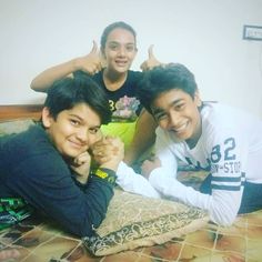 three young men are posing for a photo on a bed with their hands in the air