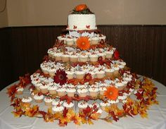 a multi tiered cake with cupcakes and leaves on the table in front of it