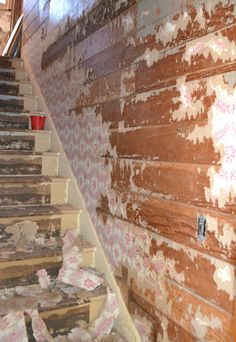 an old wooden staircase with peeling paint on the wall and carpeted steps leading up to it