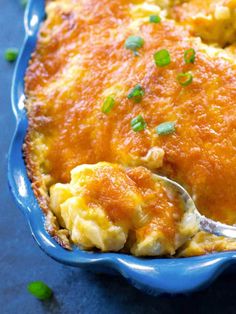 a close up of a casserole in a blue dish with a serving spoon