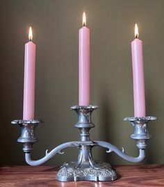 three candles are lit on a wooden table