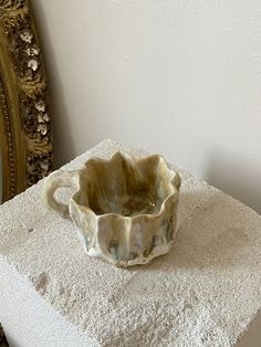 a small bowl sitting on top of a white table next to a mirror and chair