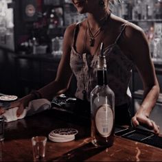 a woman sitting at a bar in front of bottles