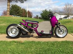 a purple scooter parked on the side of a road next to a tree