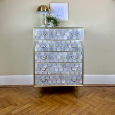 a gold and white dresser sitting on top of a hard wood floor next to a wall