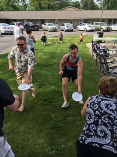 several people are playing frisbee in the grass near tables and lawn chairs at an outdoor event