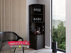 a black cabinet with wine glasses on it and a chair next to it in front of a window