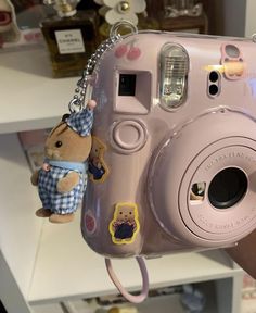 a person holding a camera with a stuffed animal attached to it's front and side