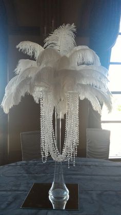 a tall vase filled with white feathers on top of a table