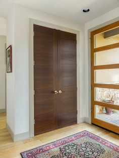 a large wooden door sitting inside of a living room next to a rug on top of a hard wood floor