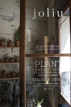 the front window of joliu with plants in pots on shelves behind it and an advertisement for plant concept store