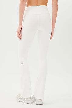 the back view of a woman in white yoga pants with her hands on her hips