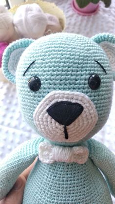 a crocheted blue teddy bear with a bow tie on it's head