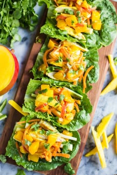 lettuce and mango salad on a wooden cutting board next to sliced peaches