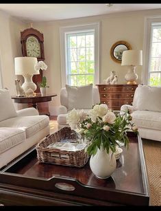 a living room filled with white furniture and lots of flowers on top of a coffee table