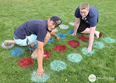 two people playing with colored chalk on the grass