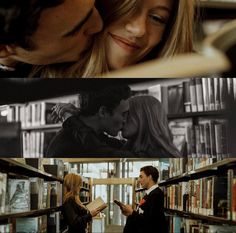 two people are kissing in front of bookshelves and one is holding a book