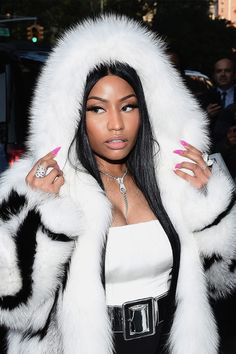 a woman with long black hair wearing a white fur coat and pink nail polishes