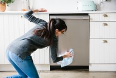 a woman bending over to pick something out of the dishwasher