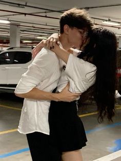 a man and woman kissing in a parking garage