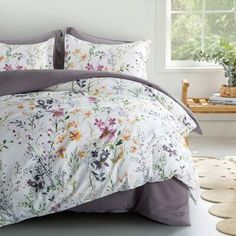 a bed with flowers on it in a room next to a window and rugs