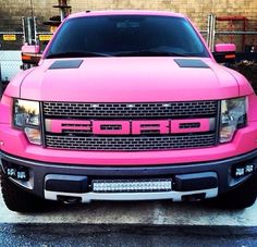 a pink pick up truck parked in front of a building