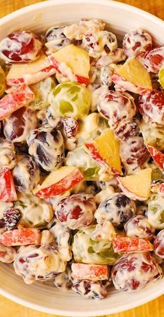 a white bowl filled with fruit salad on top of a wooden table