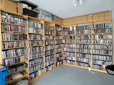 a room filled with lots of different types of dvd's on wooden shelving