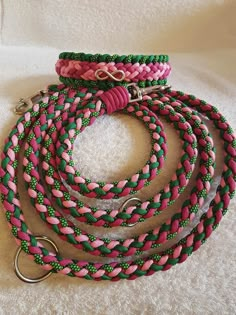 pink and green braided dog leash with metal snap hooks on white fabric background