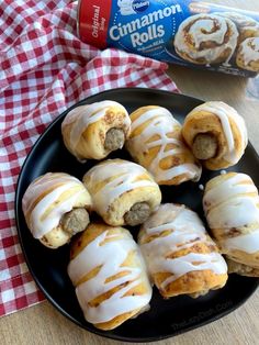 cinnamon rolls on a black plate next to a bottle of milk and a red checkered napkin