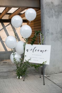 a sign and some white balloons in front of a building