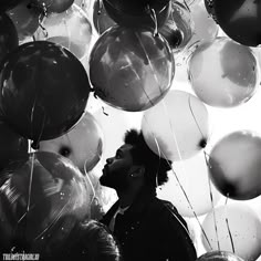 a man standing in front of a bunch of balloons