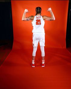 a basketball player is posing for a photo in front of a red background with his arms stretched out