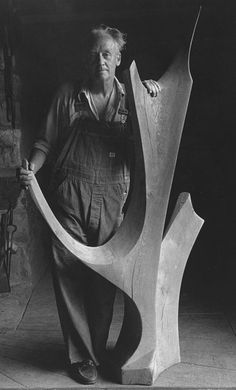 a man standing next to a large wooden sculpture