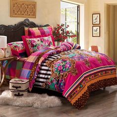 a bedroom with a bed covered in colorful comforter and pillows on top of it