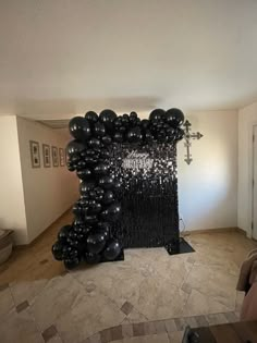 a living room filled with black balloons in the shape of an arch and chandelier