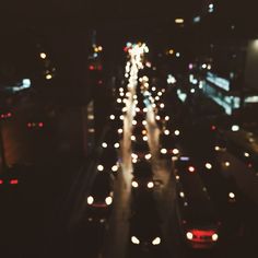 cars driving down a busy city street at night with lights on the road and buildings in the background