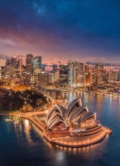 an aerial view of the sydney opera house and city skyline at night, with lights on