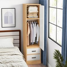 a bed room with a neatly made bed and a wooden cabinet next to a window