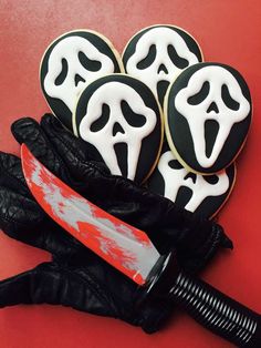 decorated cookies with black and white icing on red surface next to knife in glove