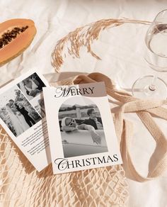 two christmas cards sitting on top of a table next to wine glasses and a cantaloupe