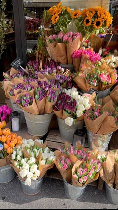 several buckets filled with different types of flowers