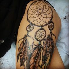 a woman's thigh with a tattoo on it that has an image of a dream catcher