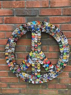 a peace sign made out of cans on a brick wall